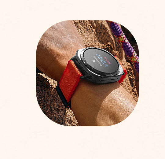Uma mão agarrando uma rocha na montanha está usando um Galaxy Watch Ultra no pulso.